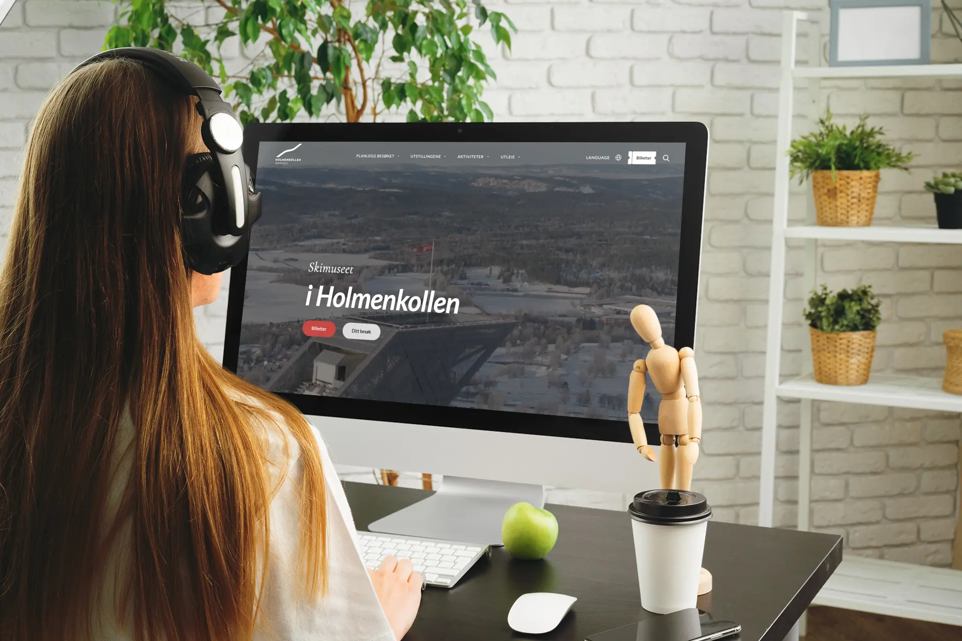 Dame med headsett ser på Mac med skjermbilde Holmenkollen