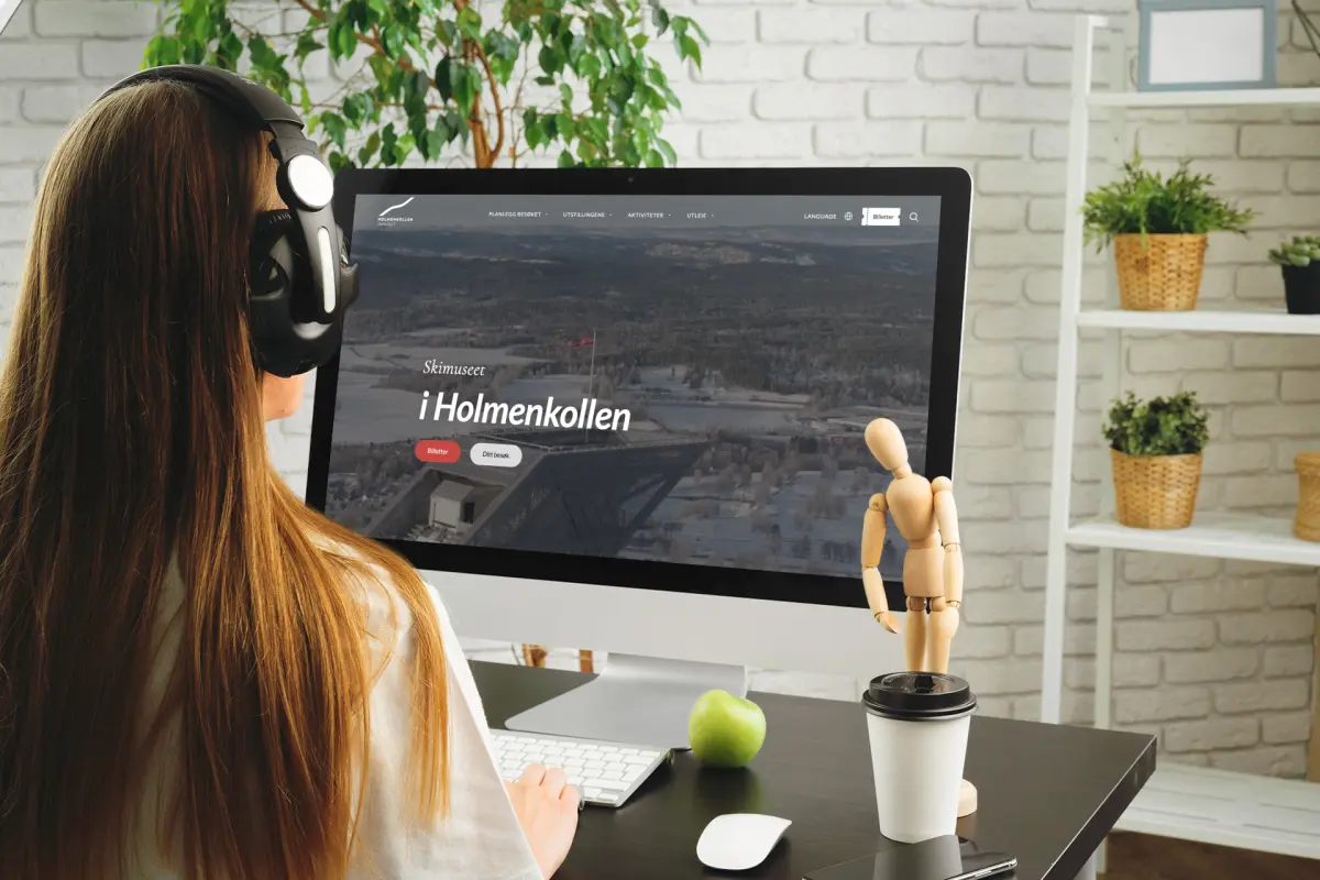 Dame med headsett ser på Mac med skjermbilde Holmenkollen