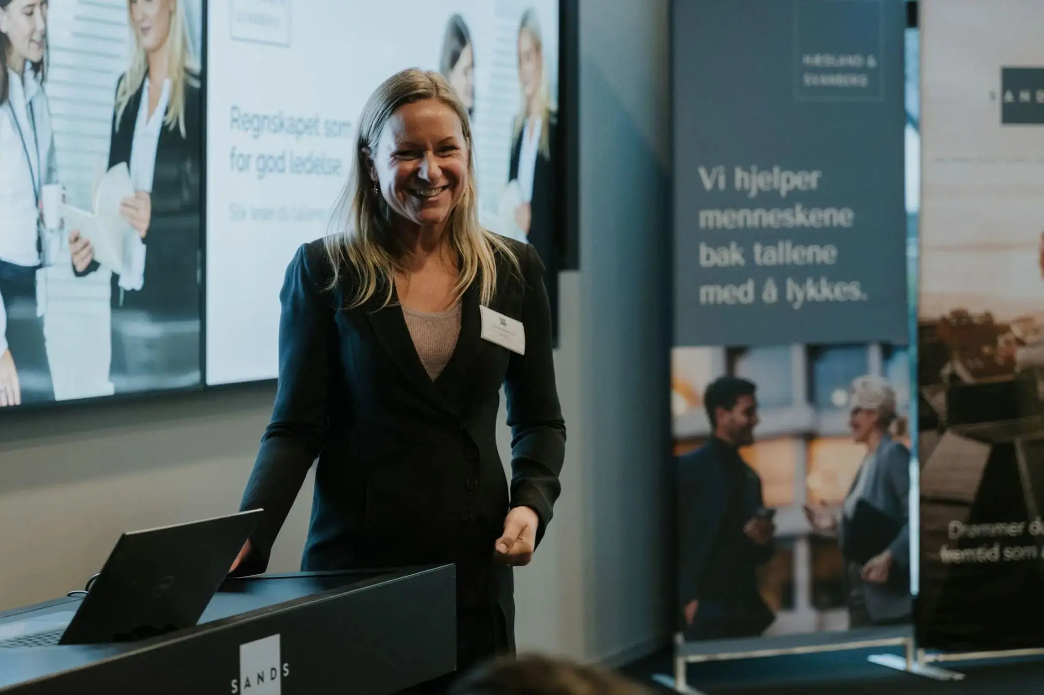 Dame som holder foredrag foran skjerm og rollup