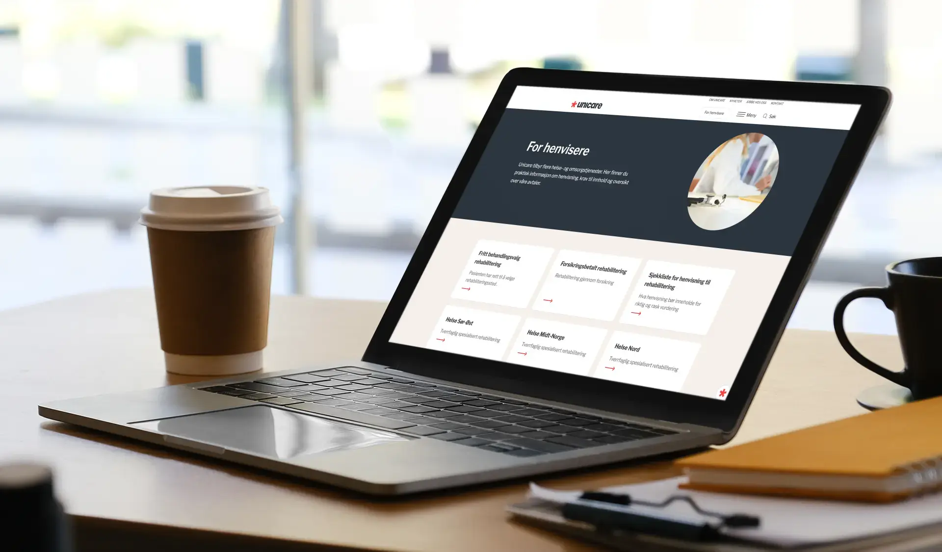 Laptop åpen på unicares nettside, omringet av kaffekopp og notatblokk
